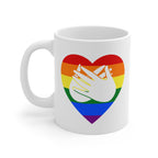 White mug with a pride coloured heart design featuring the BSL sign for Love embedded in it. The mug handle is on the left hand side of the mug.