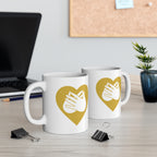 Two mugs with gold coloured heart designs featuring the BSL sign for Love embedded in them on a desk with office supplies.