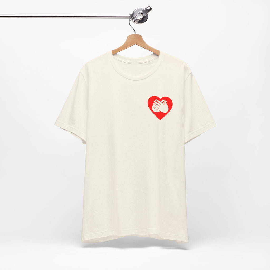 Front view of a natural T-Shirt showing a red coloured heart and the iconic BSL Love sign embedded in it on the left side of the chest, on a hanger against a white background
