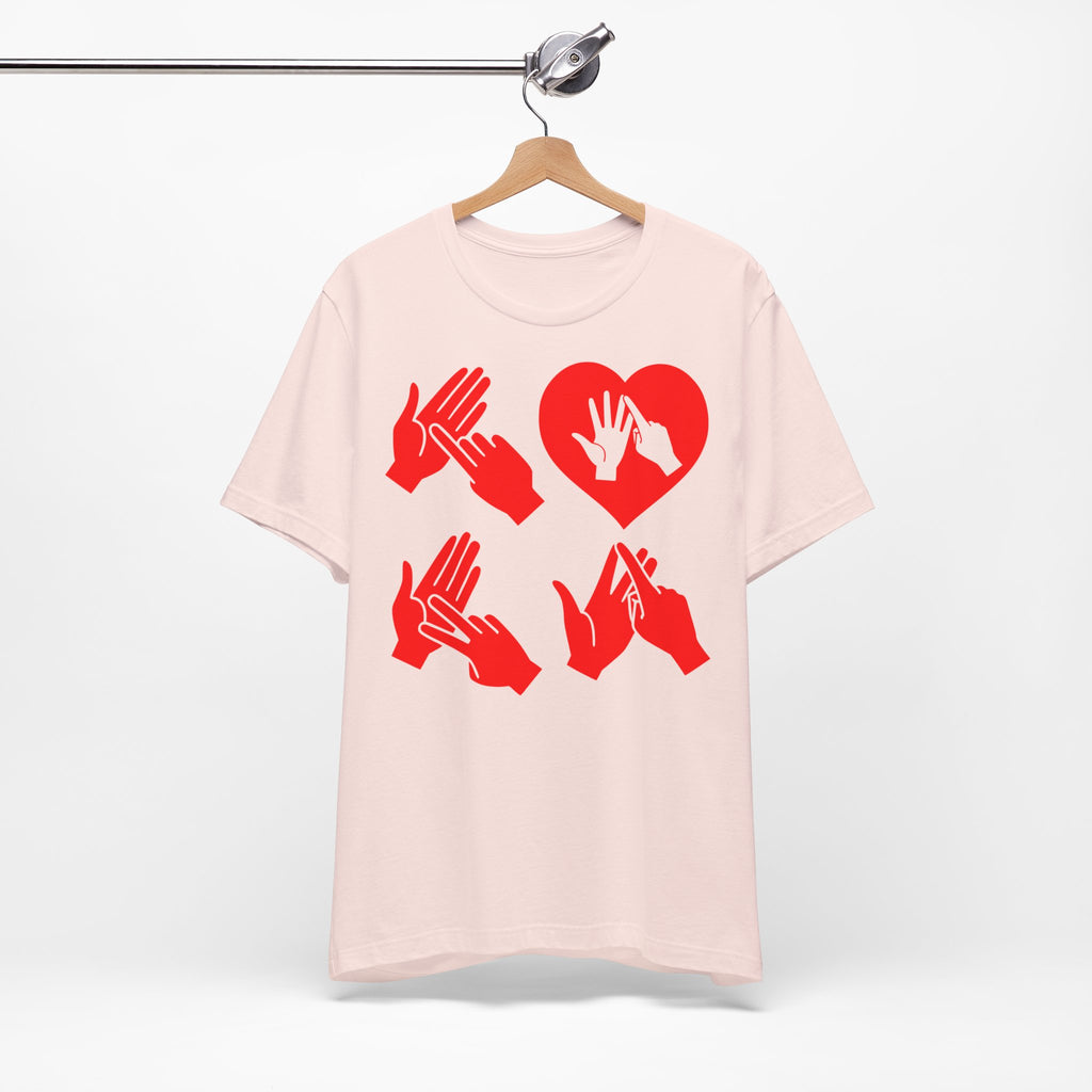 Front view of a soft pink T-Shirt with the word Love in red BSL Fingerspelling with the 'O' embedded in a heart shape, on a hanger against a white background