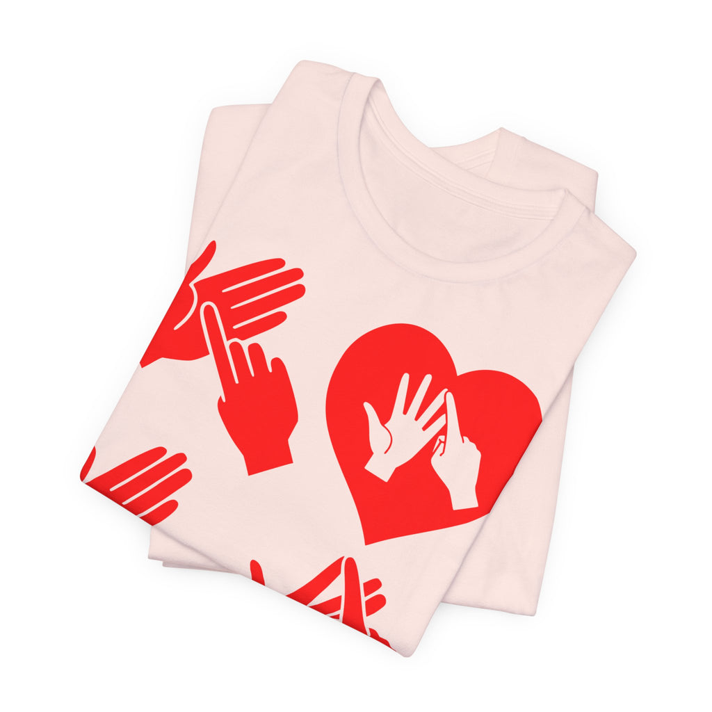 Folded soft pink T-Shirt with the word Love in red BSL Fingerspelling with the 'O' embedded in a heart shape