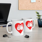 Two mugs with red coloured heart designs featuring the BSL sign for Love embedded in them on a desk with office supplies.