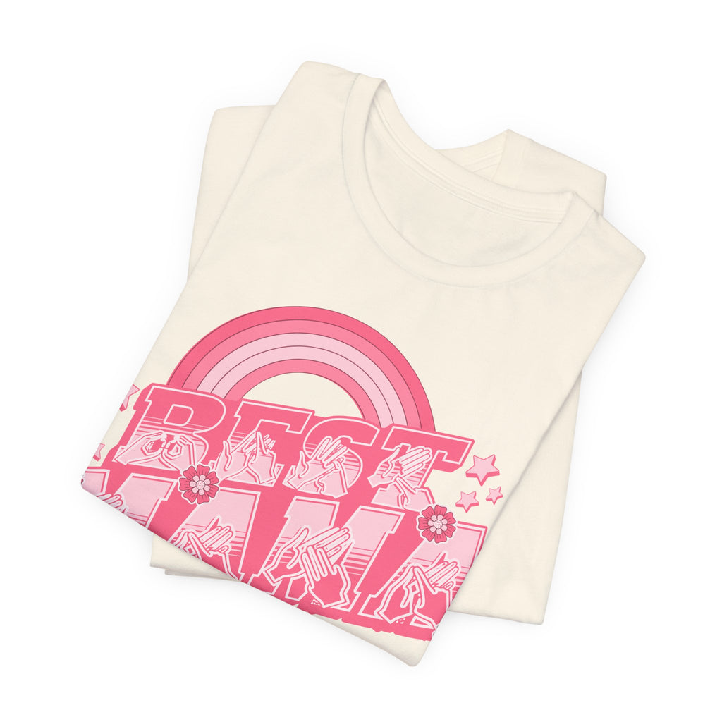 Folded Natural T-shirt with ‘Best Mama’ shown in BSL fingerspelling and text, with rainbow, stars, and floral accents