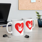 Two mugs with red coloured heart designs featuring the ASL sign for I Love You embedded in them on a desk with office supplies.