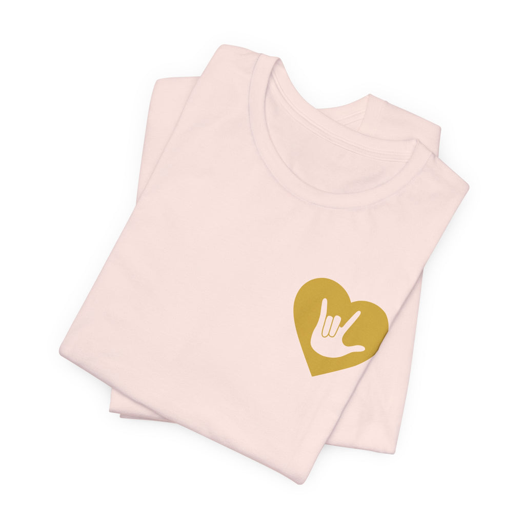 Folded soft pink T-Shirt showing a gold coloured heart and the iconic ASL I Love You sign embedded in it on the left side of the chest