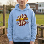 Child wearing a light blue hoodie with a design and text outdoors.