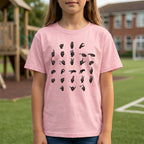 Child wearing a pink t-shirt with black hand signs on a grassy field.