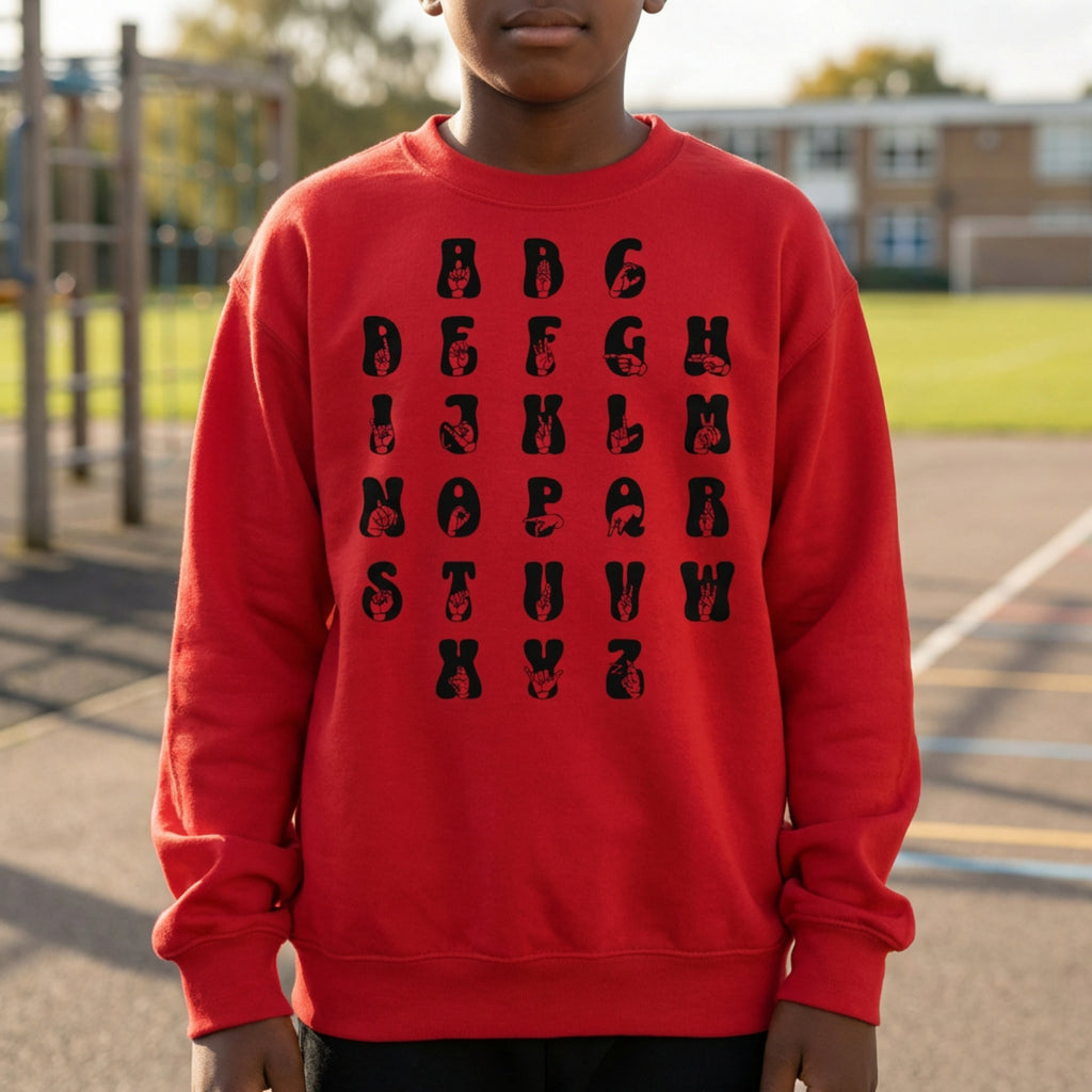 Person wearing a red sweatshirt with black alphabet letters outdoors.