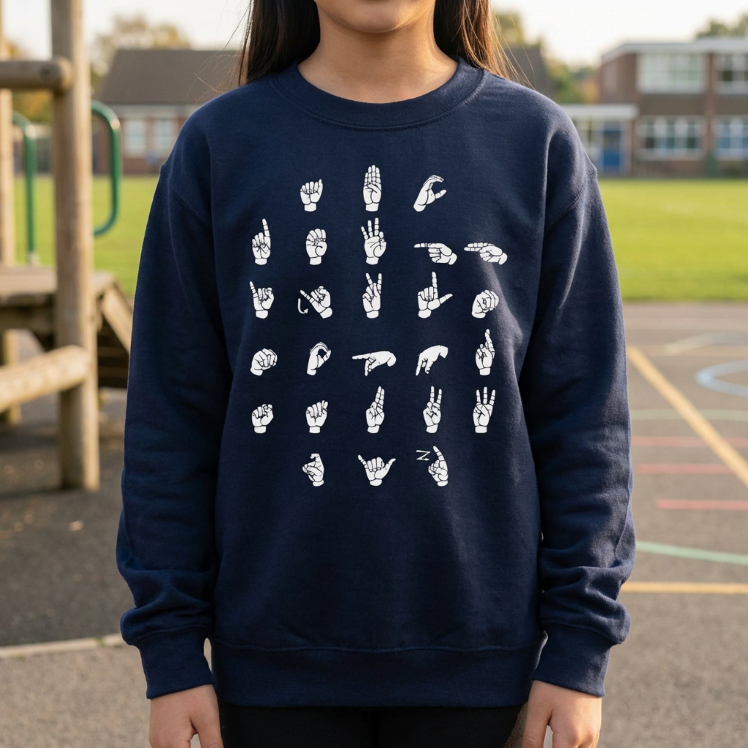 Person wearing a navy blue sweatshirt with white hand signs on a playground background