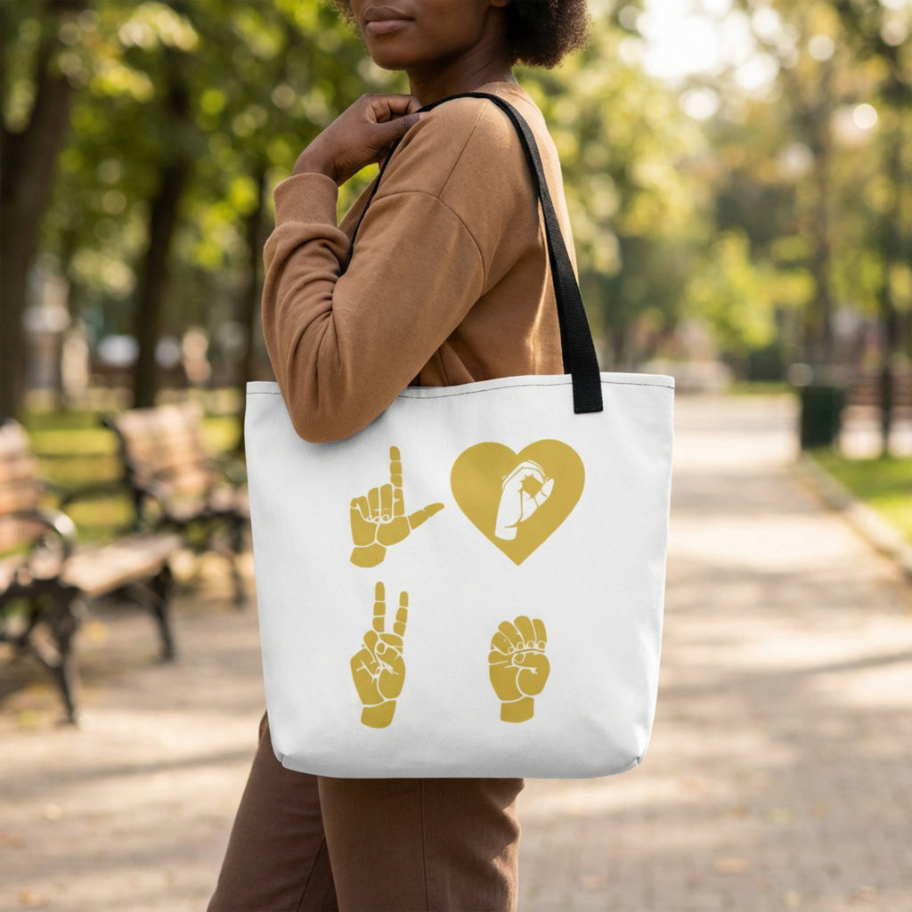 Person holding a tote bag with gold symbols in a park