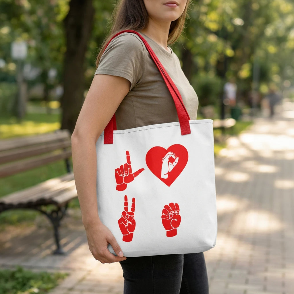 Person holding a white tote bag with red designs in a park