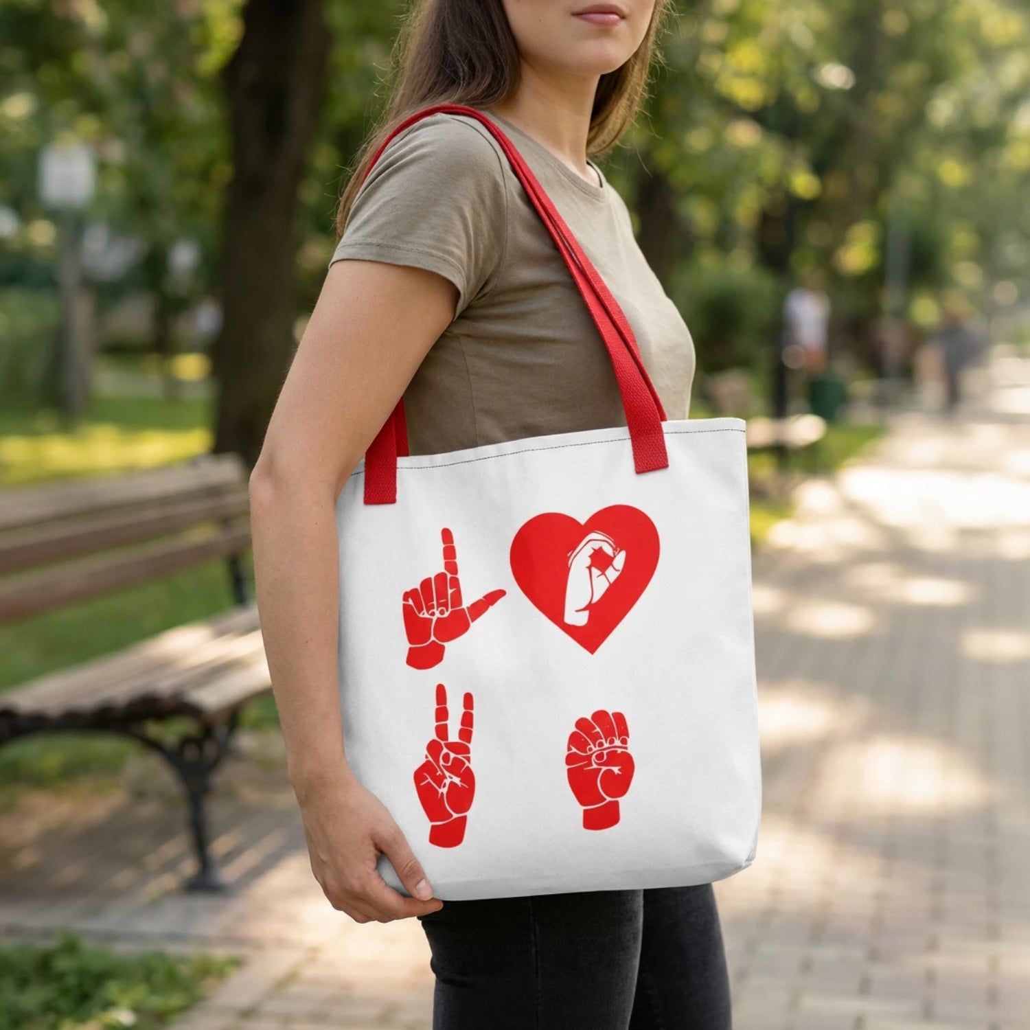 Person holding a white tote bag with red designs in a park