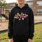 A person wearing a black hoodie with ‘Always Be Kind’ in BSL fingerspelling and text, accented by a floral design