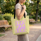 Person holding a green tote bag with a purple design in a park