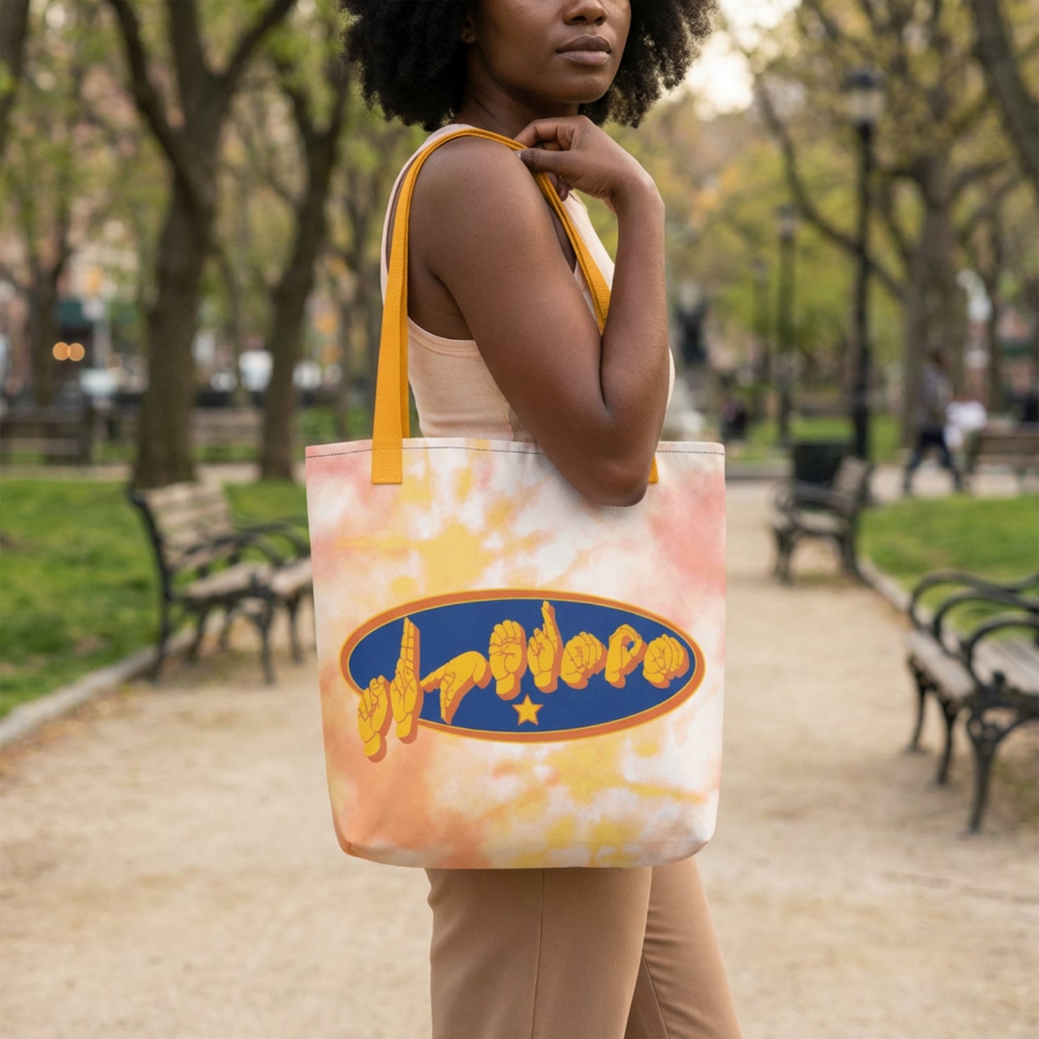 Person holding a tote bag with a colorful design in a park