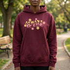 Person wearing a maroon hoodie with floral text in a park