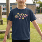 Child wearing a navy blue t-shirt with colorful text and flower graphics on a school playground.