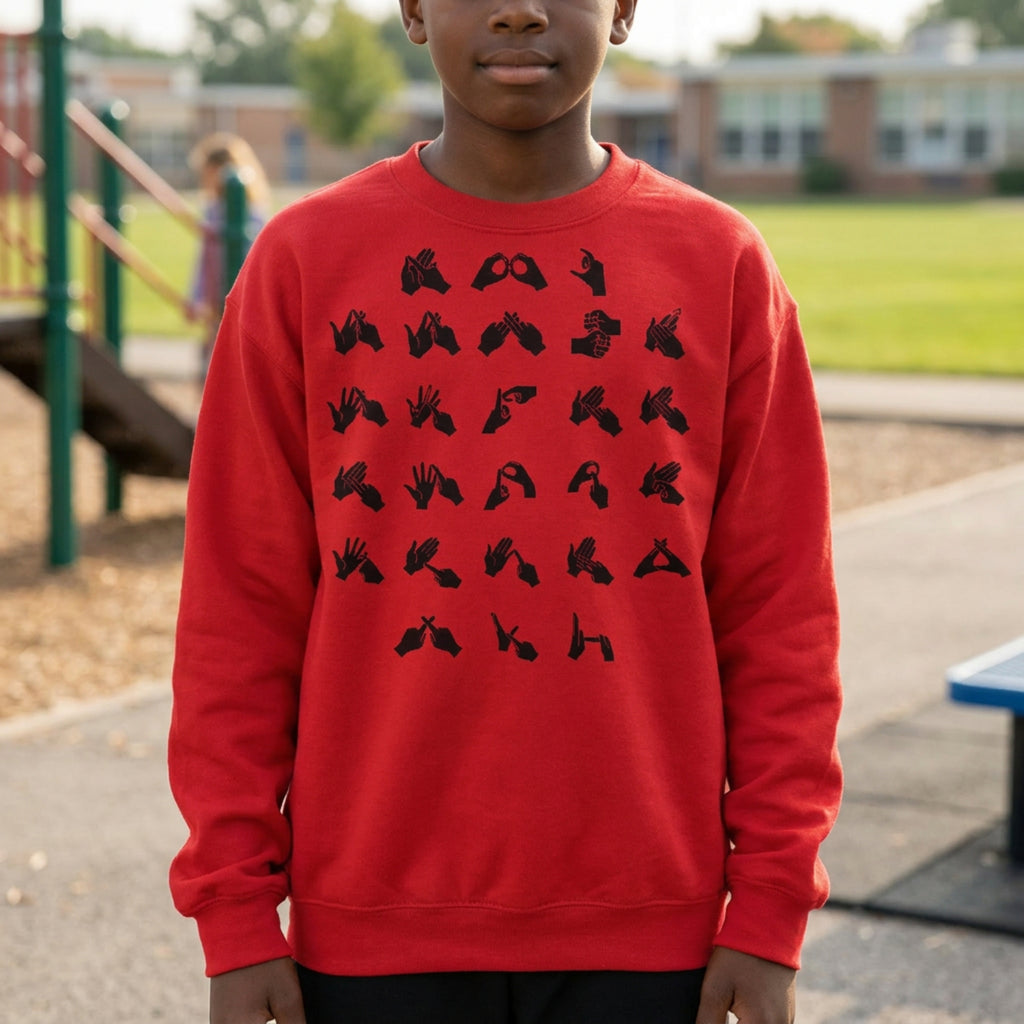 Child wearing a red sweatshirt with black fingerspelling design on a playground background