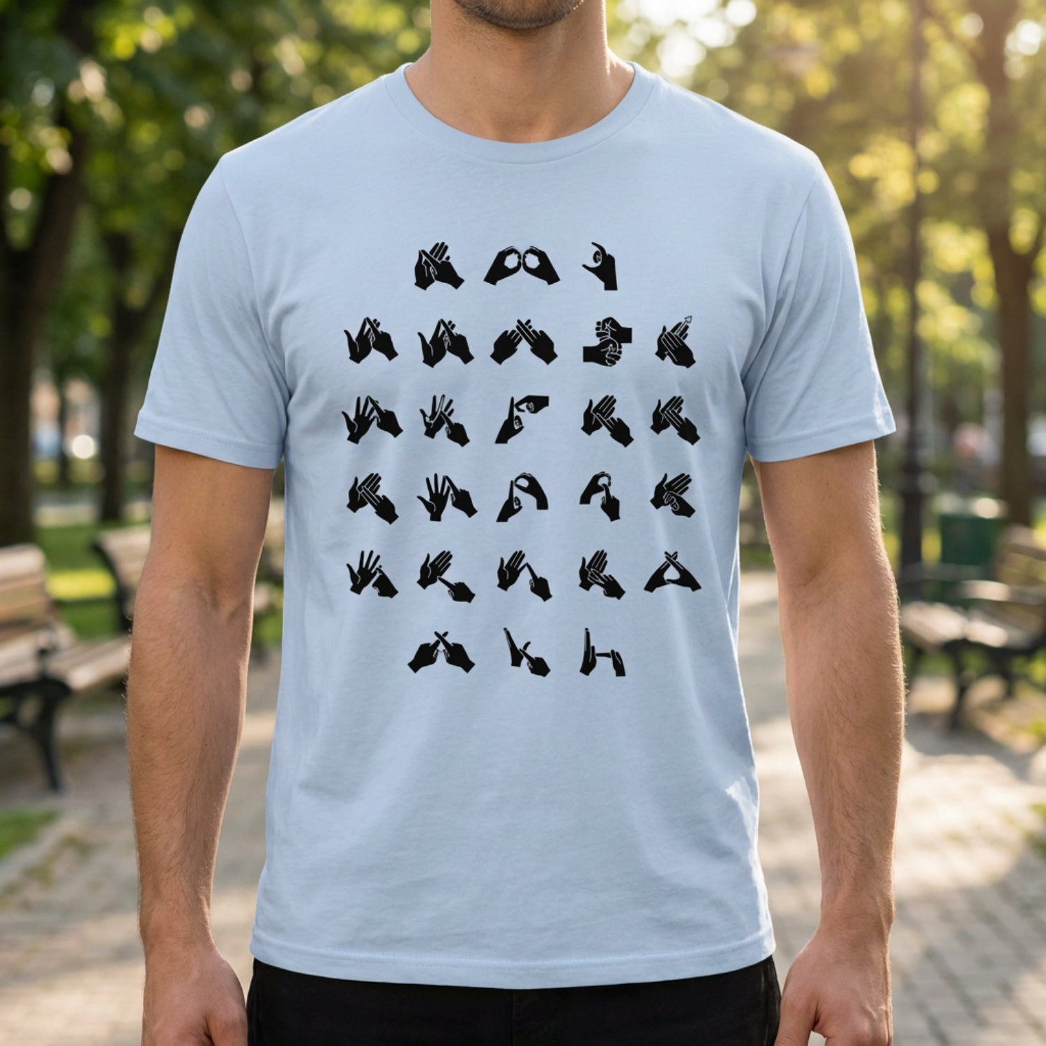 Person wearing a light blue t-shirt with black fingerspelling design in an outdoor setting.