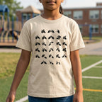 Child wearing a beige t-shirt with black fingerspelling design on a school playground.