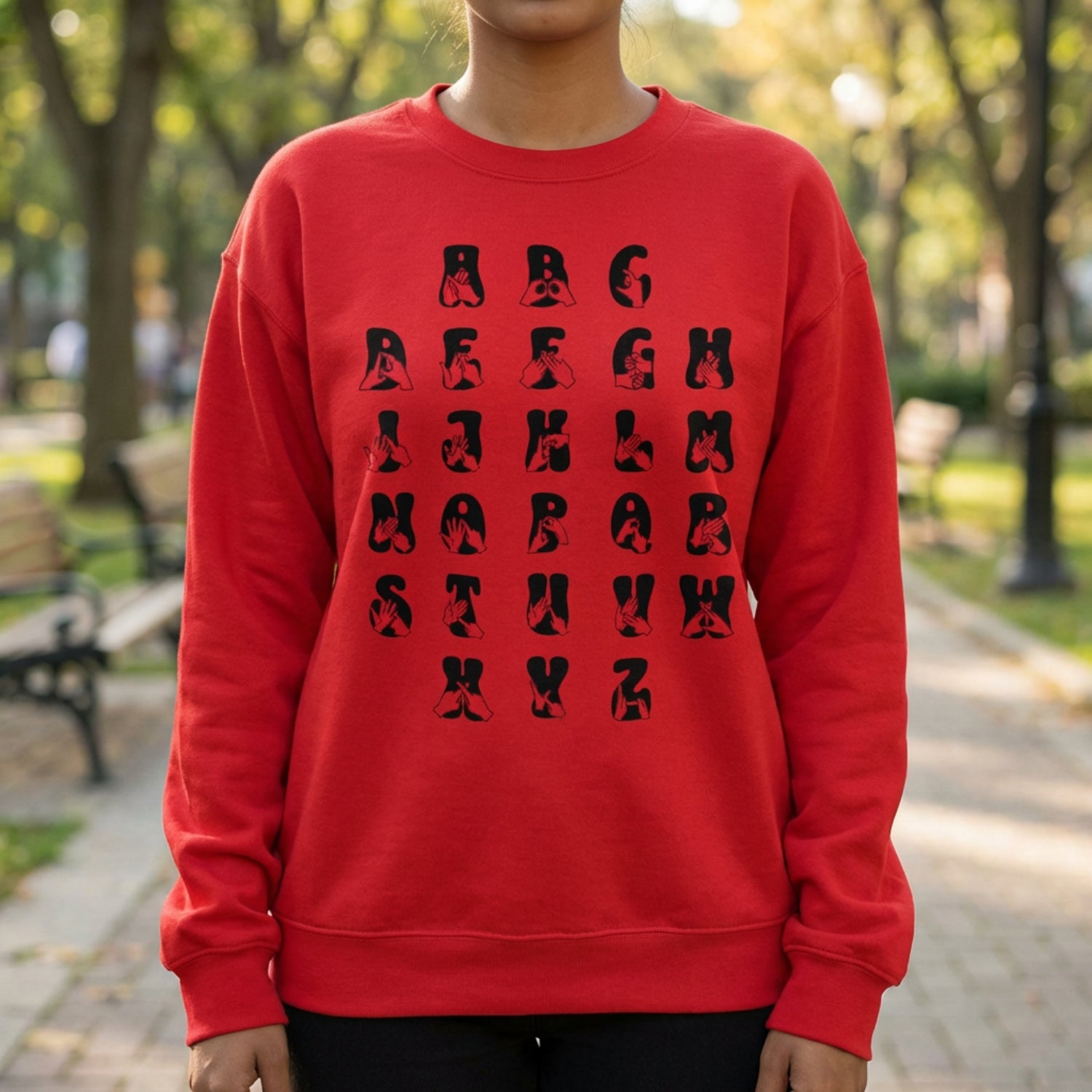 Person wearing a red sweatshirt with black alphabet design in an outdoor setting