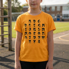 A person wearing a gold t-shirt with BSL Alphabet - Black Fingerspelling & Text