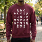 Person wearing a maroon sweatshirt with white alphabet letters outdoors.