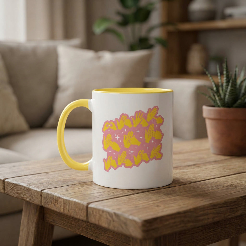 White mug with yellow interior and pink and yellow design on a wooden table in a cozy living room.