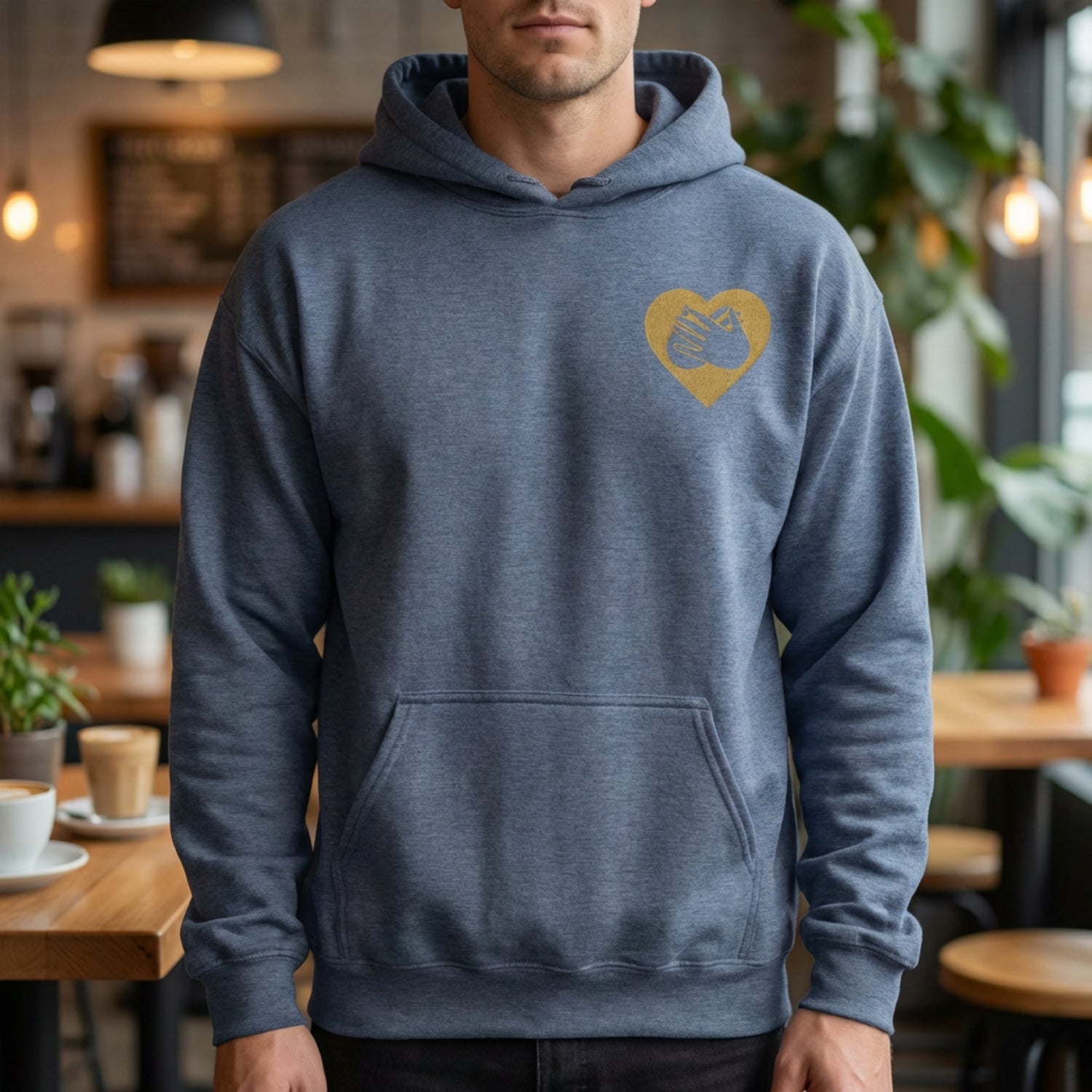 Person wearing a blue hoodie with a yellow heart design in a casual setting
