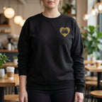 Person wearing a black sweatshirt with a gold heart design in a casual setting
