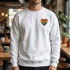 Person wearing a white sweatshirt with a pride rainbow heart design in a casual setting