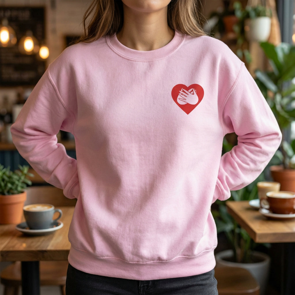 Person wearing a pink sweatshirt with a red heart design in a casual setting