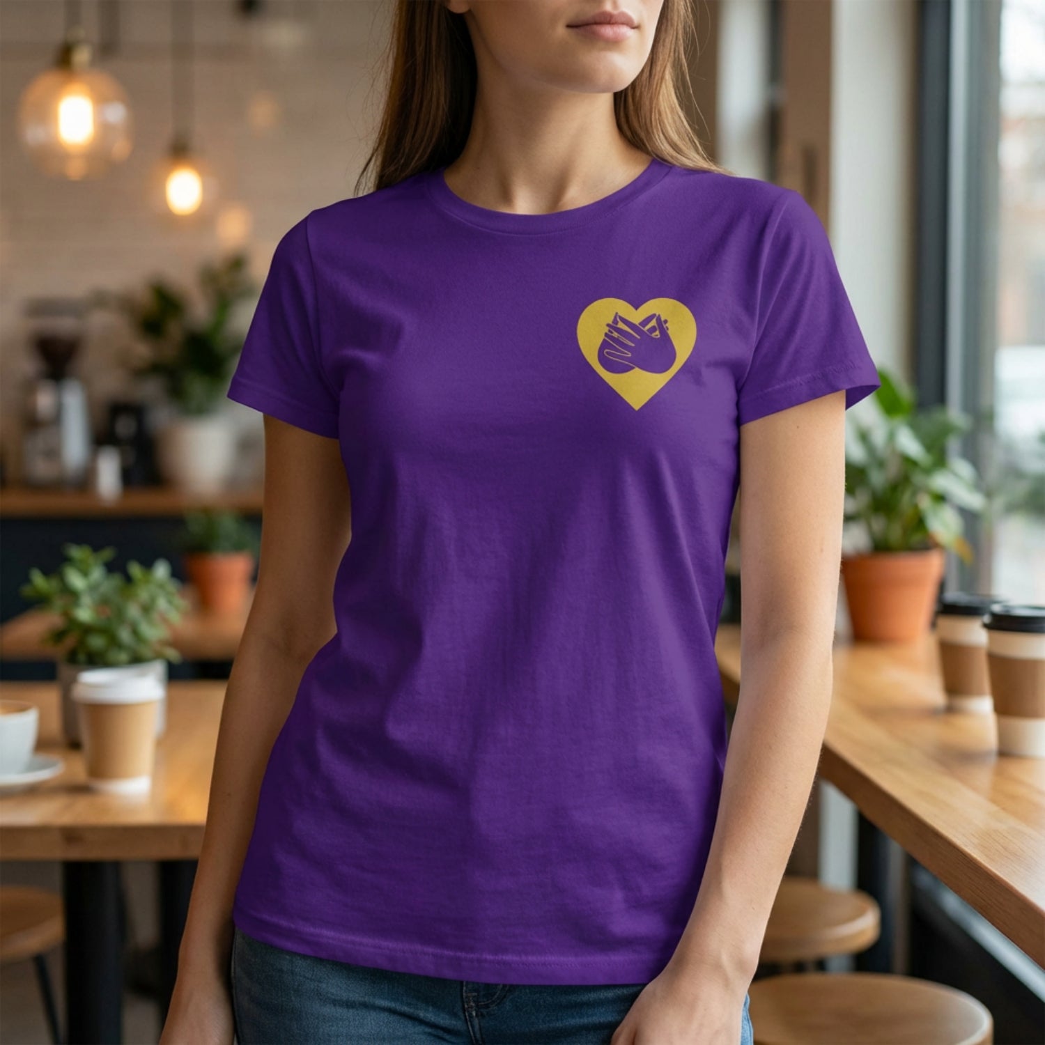 Person wearing a purple t-shirt with a gold heart design in a casual setting