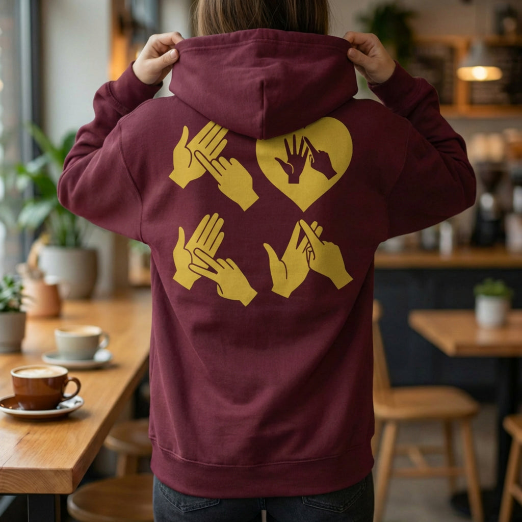 Back view of a person wearing a hoodie with gold fingerspelling design.