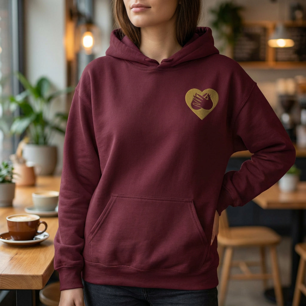 Person wearing a maroon hoodie with a heart design in a cafe setting