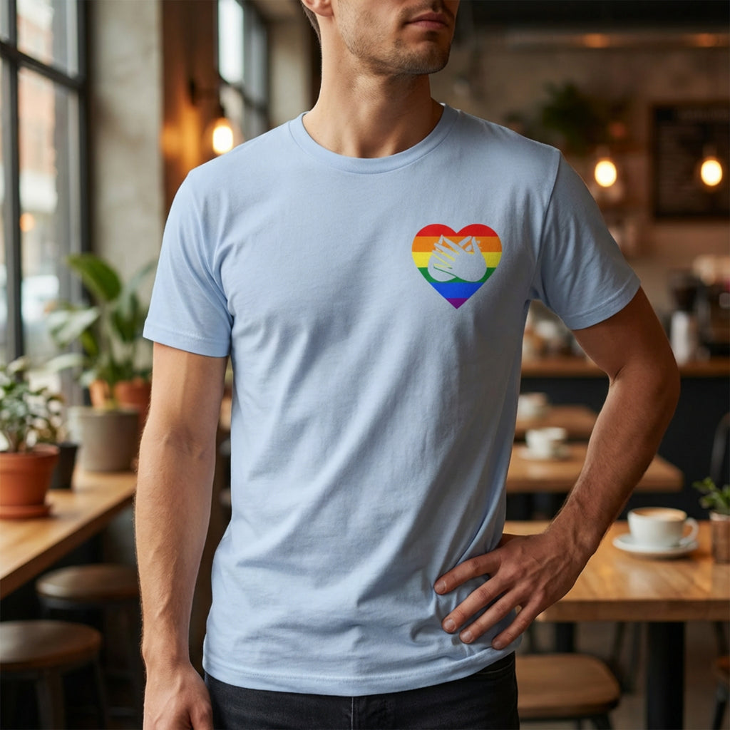 Man wearing a light blue t-shirt with a rainbow heart design in a casual setting.