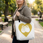 Woman holding a tote bag with a heart and hand design in a park.