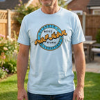 Man wearing a light blue t-shirt with a graphic design in a garden setting