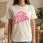 Person wearing a white t-shirt with a pink graphic design in a home setting