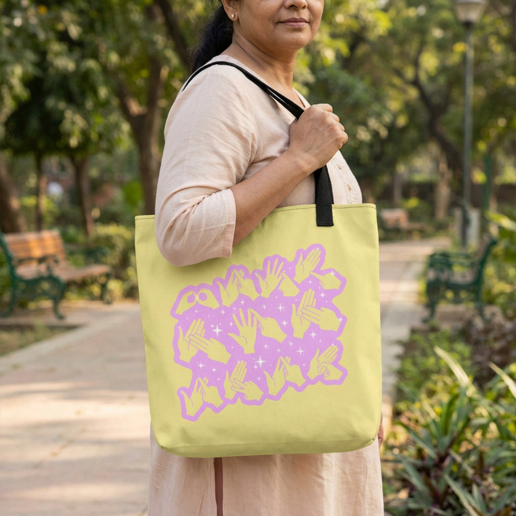 Woman holding a lime green tote bag with a purple design in a park.