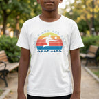 Person wearing a white t-shirt with a colorful graphic design outdoors.