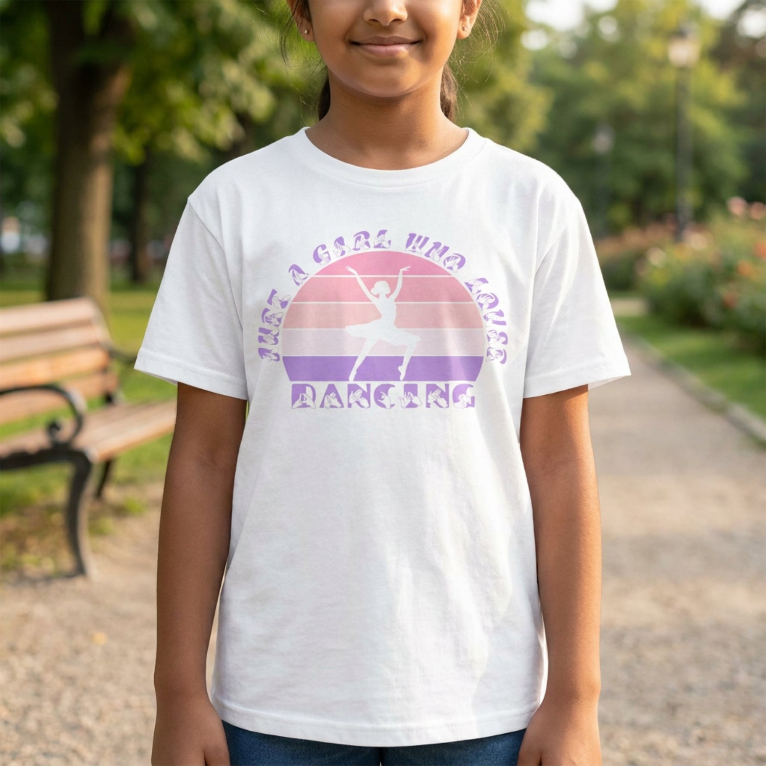 A girl wearing a white t-shirt with the phrase "Just a Girl Who Loves Dancing" above a colourful retro sunset and a silhouette of a girl dancing in the centre