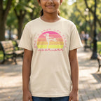 A person wearing a natural t-shirt with the phrase "Just a Girl Who Loves Football" in BSL Fingerspelling featuring a colourful retro sunset and a silhouette of a girl kicking a football.