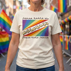 Person wearing a t-shirt with a rainbow design and text, standing in front of rainbow flags.