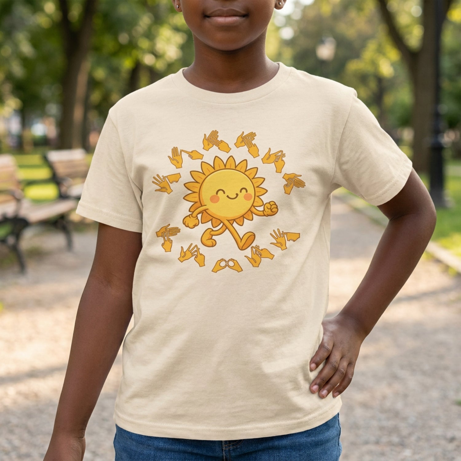 Child wearing a beige t-shirt with a sun design in a park