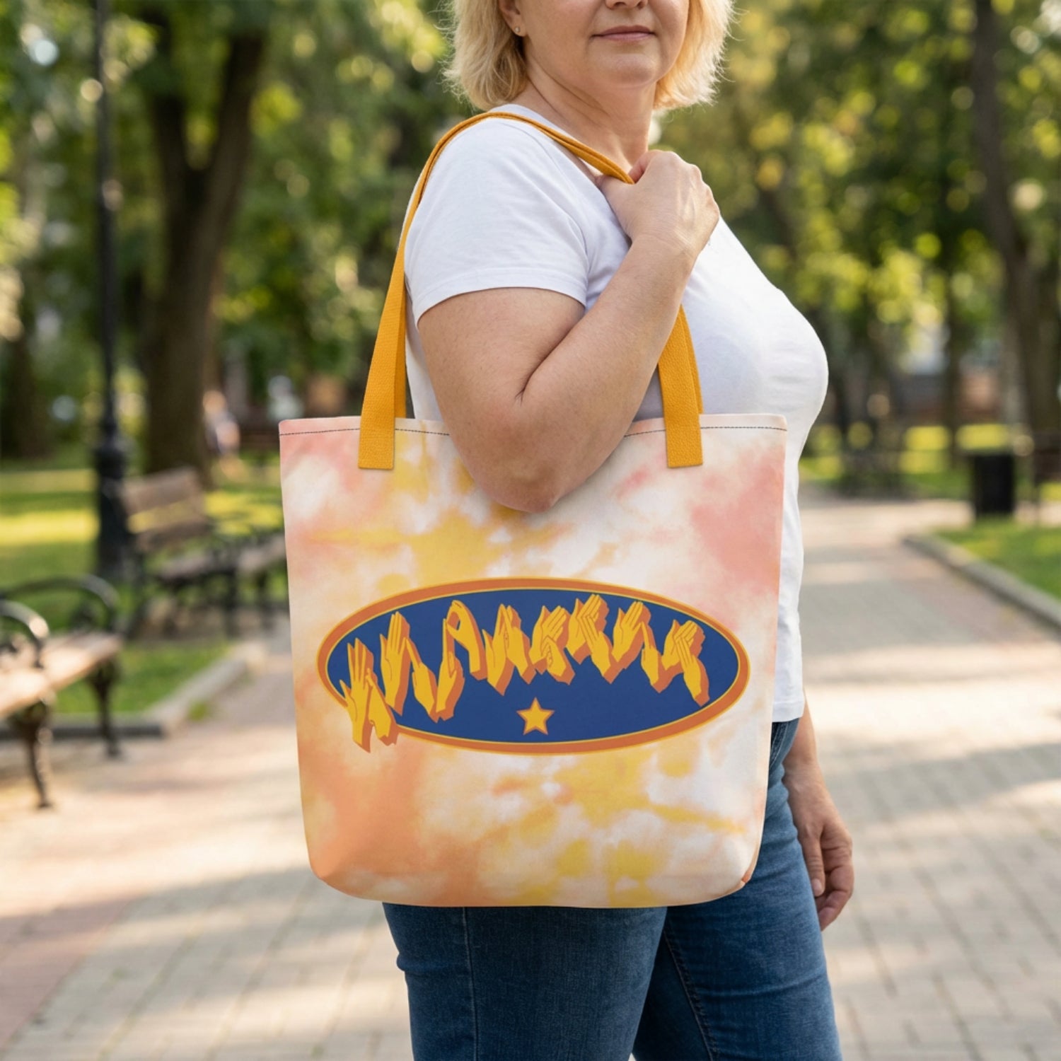 Person holding a tote bag with a logo in a park