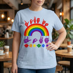 A person wearing a light blue t-shirt with pride rainbow surrounded by the phrase "Love Is Love" in ASL fingerspelling