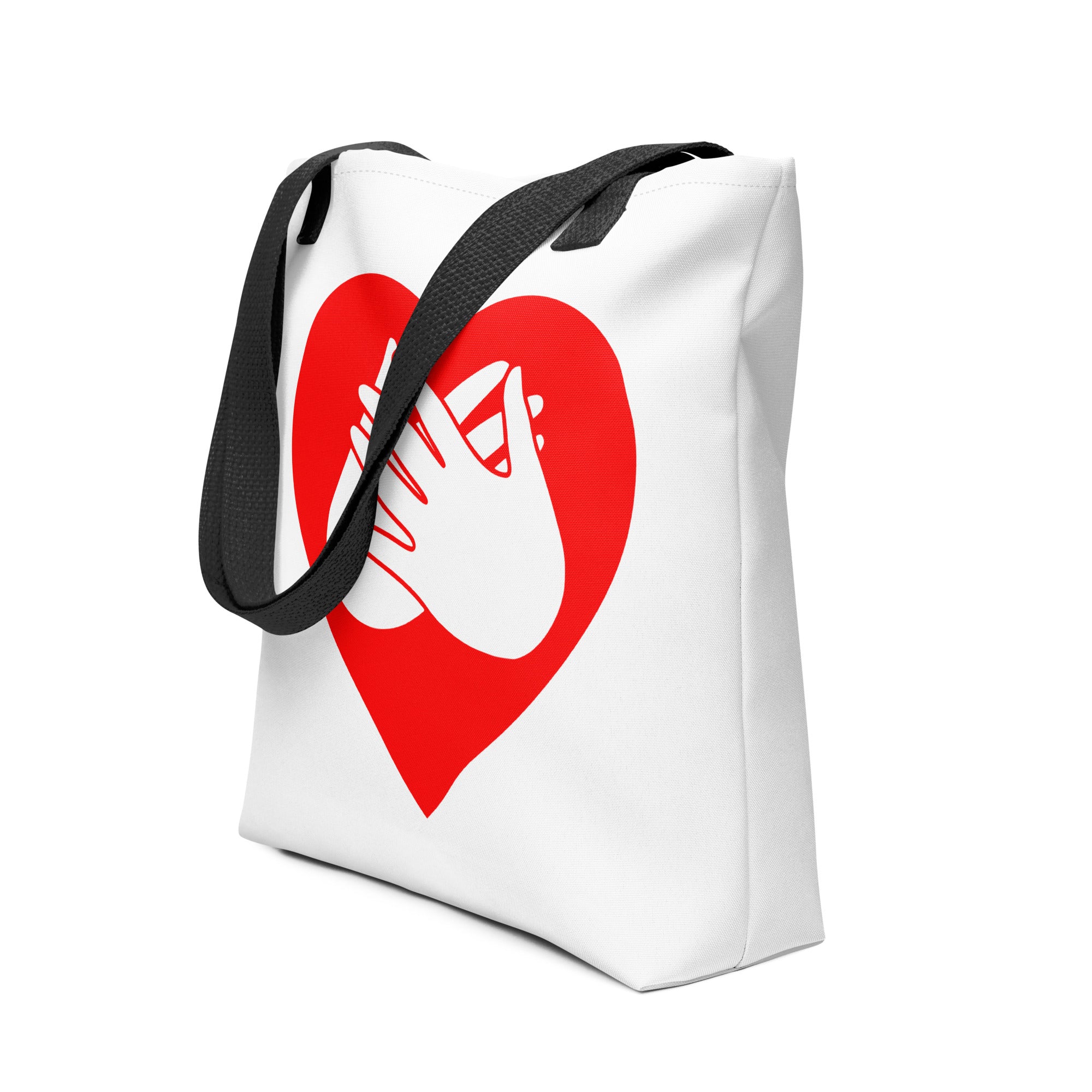 An angled view of a white Tote bag with a black handle and a red heart with the BSL love sign at its centre.
