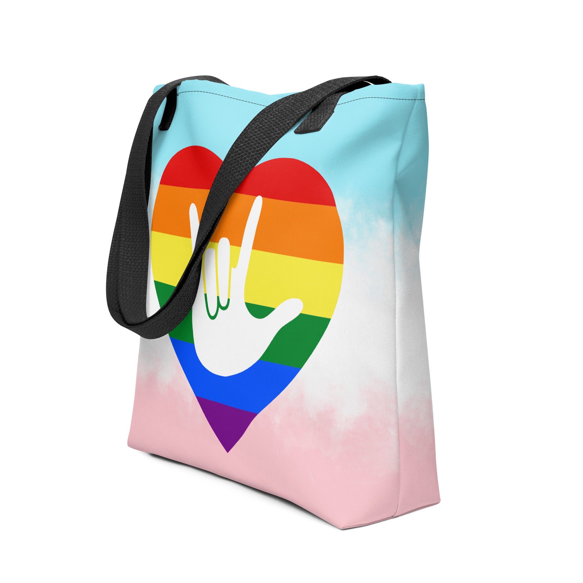 An angled view of a white Tote bag with a black handle and a pride heart with the ASL I love you sign at its center.