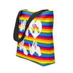 An angled view of a pride rainbow coloured tote bag with a black handle and the word LOVE in white BSL fingerspelling design